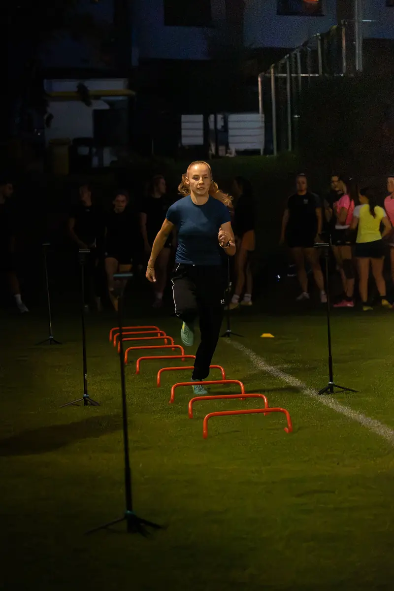 Sportovkyně při běhu přes překážky mezi měřicími bránami